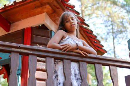 Little girl Indian leaned on the fence and looking downの写真素材