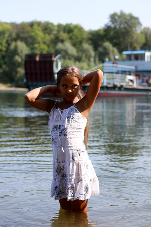 girl in a white dress standing in the riverの写真素材