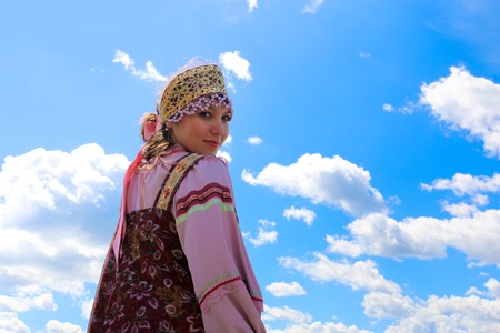 Portrait of a young girl in Russian folk costume on the sky backgroundの写真素材