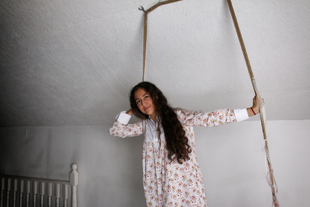 Portrait of young Hispanic woman in a nightgown on swingの写真素材