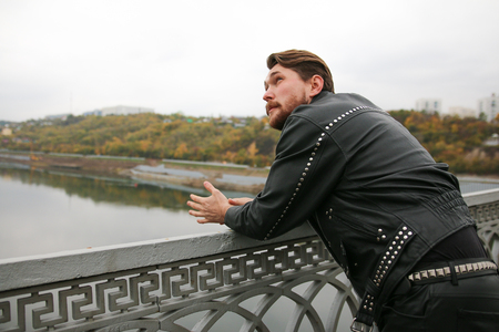 Man in black leather jackets looking at riverの写真素材
