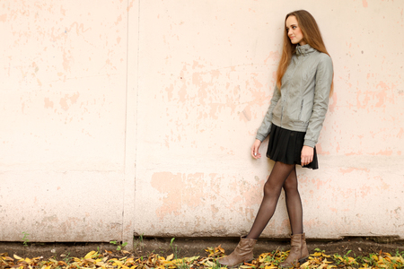 Fashion girl with long hair wearing black skirt, trench coat and gray leather jacketの写真素材