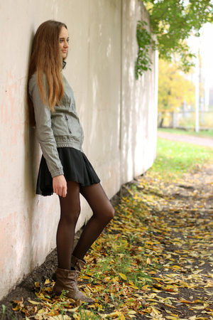 Fashion girl with long hair wearing black skirt, trench coat and gray leather jacketの写真素材
