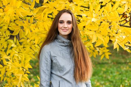 Beautiful young woman in leather jacket and black skirt posing in autumn park.の写真素材