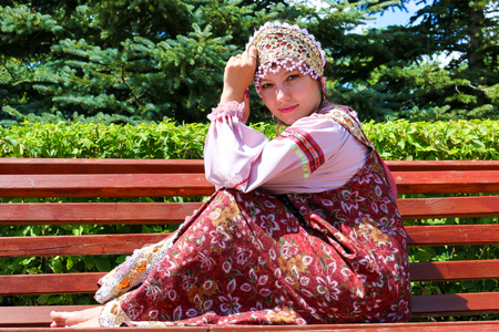 Young girl in Russian folk costume sits on the benchの写真素材