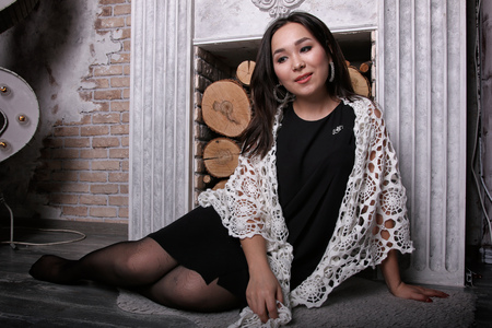 Asian girl in torn pantyhose sitting near the fireplace with the shawl on his shouldersの写真素材