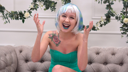 Excited woman looking at you sitting on a sofa in the living room at homeの写真素材
