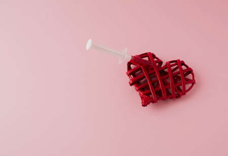 Red syringe in red heart on pink background. Romantic concept in time of corona.の写真素材