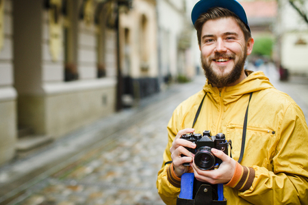 Young man with oldschool camera, laughing, soft-focusの写真素材