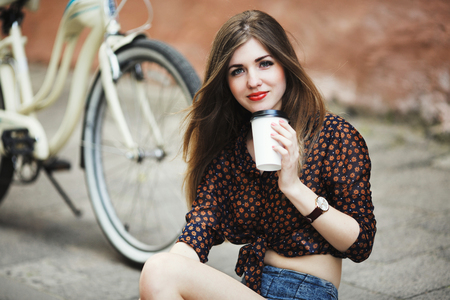 Girl is posing with coffee on tiled pavement in old cityの写真素材