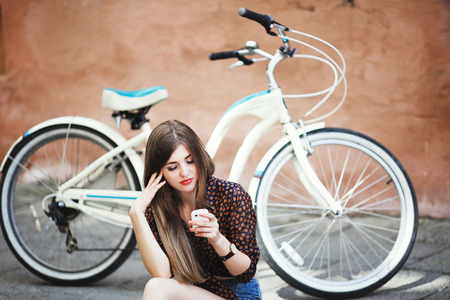 Beautiful girl wearing on dark blouse is sitting on tiled pavement in old cityの写真素材