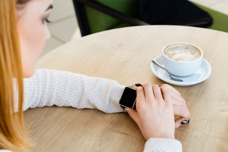 Girl wearing watch, cup of coffee on tableの写真素材