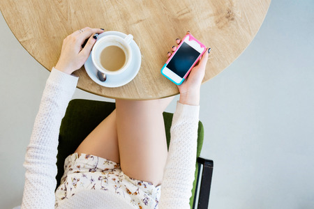 Girls legs, cup of coffee and mobile phoneの写真素材