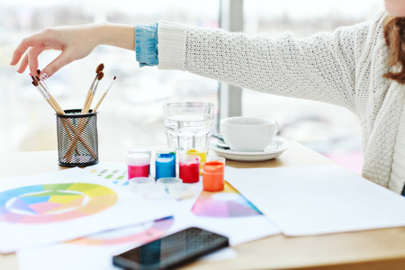 Womans hands with white manicure touching paint brushの写真素材