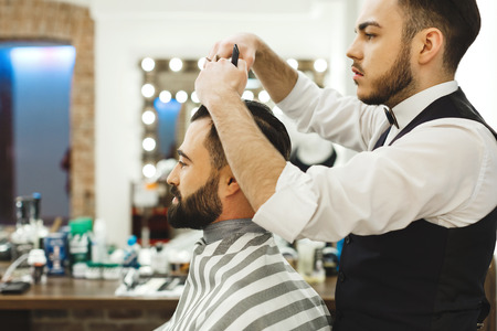 Dark haired barber doing a haircutの写真素材
