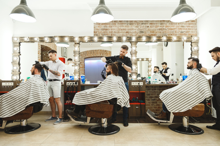 Barbers doing haircuts for clientsの写真素材