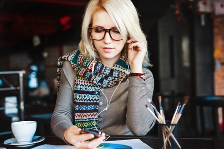 Blonde girl with mobile phone and headphonesの写真素材