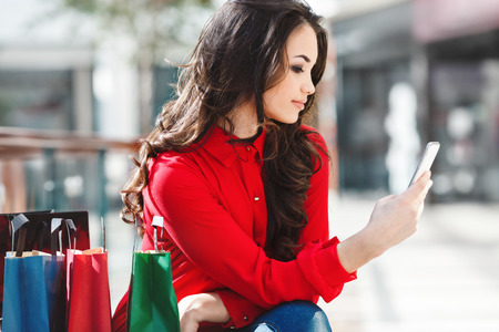 Beautiful girl sitting in mall with colorful bagsの写真素材