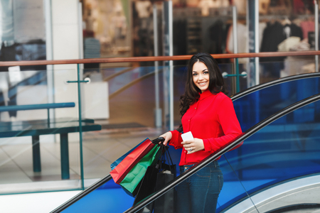 Nice girl on escalator with shopping bagsの写真素材
