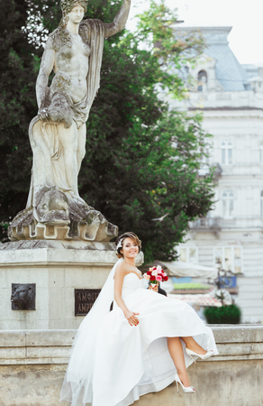 Beautiful bride sitting near monumentの写真素材