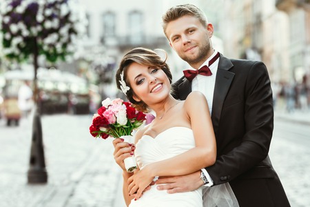 Bride and bridegroom holding bouquet and smilingの写真素材