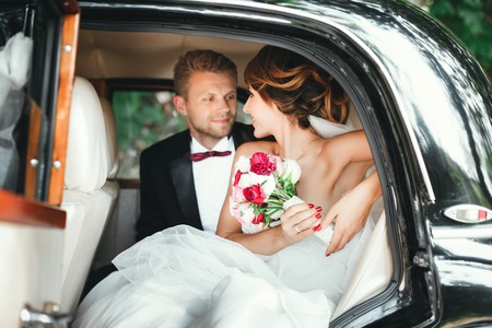 Bride and groom sitting in wedding carの写真素材