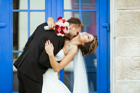 Bride and groom embracing near blue doorの写真素材