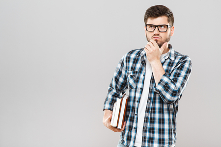 Thoughtful man holding colorful booksの写真素材