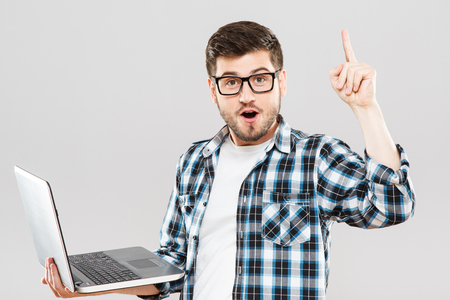 Young man in glasses with laptop has ideaの写真素材
