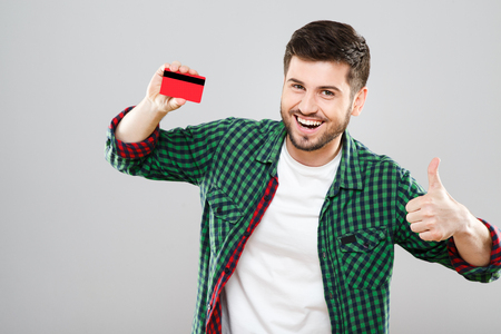 Man holding red credit card and showing thumbs upの写真素材