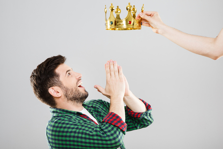 Surprised young man with crown above his headの写真素材