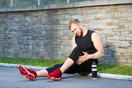 Sportsman sitting and holding his legの写真素材