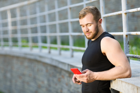 Sportsman standing with red mobile phoneの写真素材