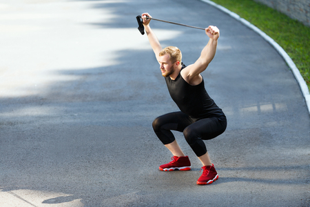 Sportsman squatting with expanderの写真素材