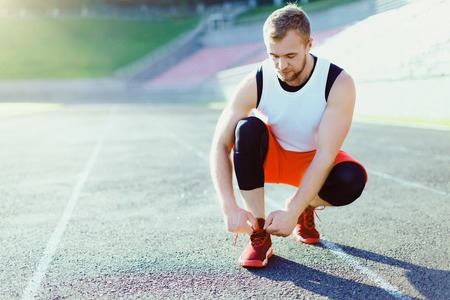 Man crouched in red sneakers