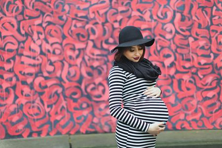 Pregnant girl standing near colorful wall