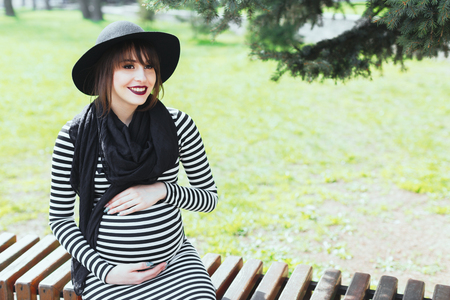 Pregnant girl sitting on bench and smilingの写真素材