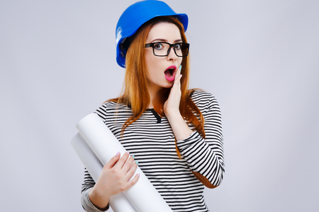 Surprised girl in helmet with sheet of paperの写真素材