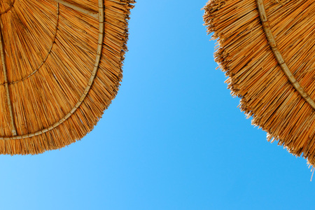 Beach umbrellas made of straw at blue sky backgroundの写真素材