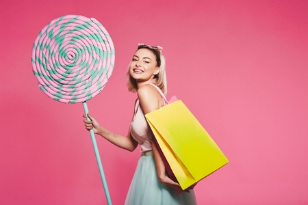 Model posing with with sweets and shopping bagsの写真素材