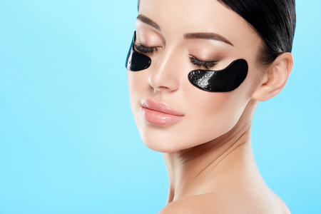 Pretty girl with nude make up and naked shoulders at studio background,black eye patches on face, skin treatment, SPA concept.の写真素材