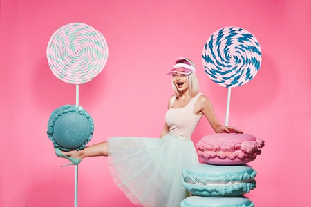 Beautiful girl posing with sweets at pink backgroundの写真素材