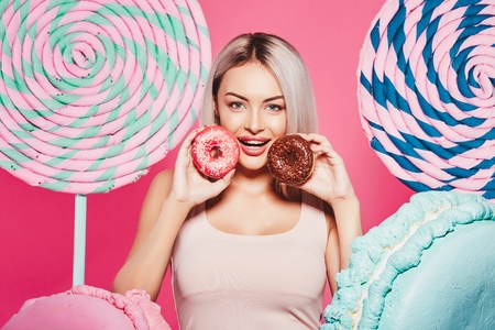 Beautiful girl posing with sweets at pink backgroundの写真素材