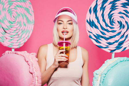 Beautiful girl posing with sweets at pink backgroundの写真素材