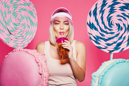 Beautiful girl posing with sweets at pink backgroundの写真素材