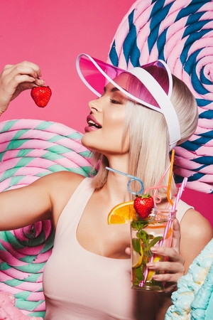Beautiful girl drinking lemonade at pink backgroundの写真素材