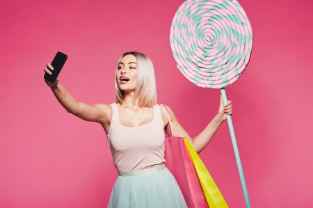 Model posing with with sweets and shopping bagsの写真素材