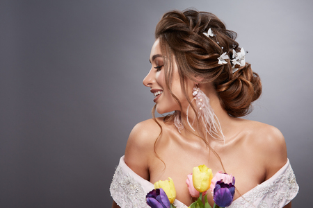 profile of laughing bride with open shoulders and flowers on grey backgroundの写真素材