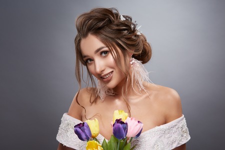 happy bride on grey background with flowers smilingの写真素材