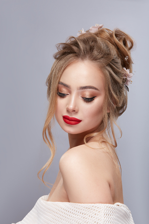 portrait of woman with blond hair and red lips looking down to her shoulderの写真素材
